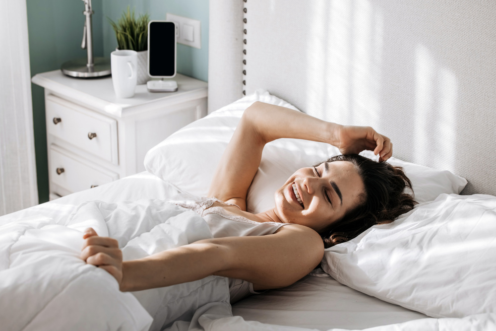 A smiling woman waking up in the morning in a cozy home setting. Concept of a comfortable morning