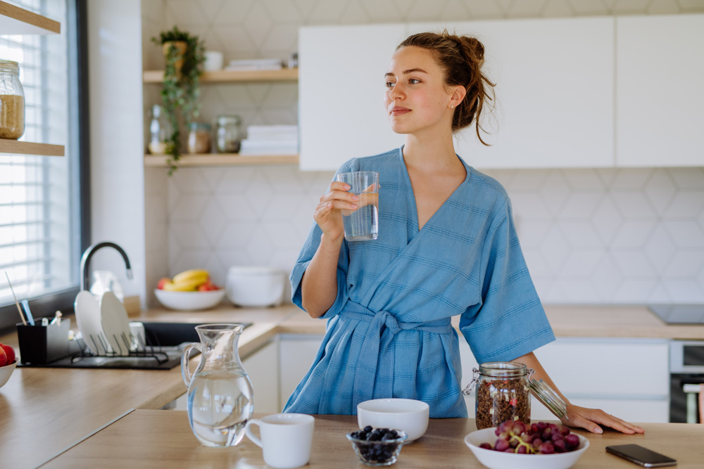 Young woman preparing a muesli for breakfast in her kitchen, morning routine and healthy lifestyle concept