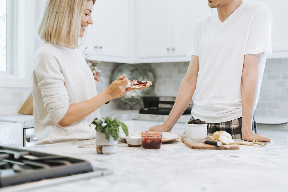 man and woman eating bread in the kitchen