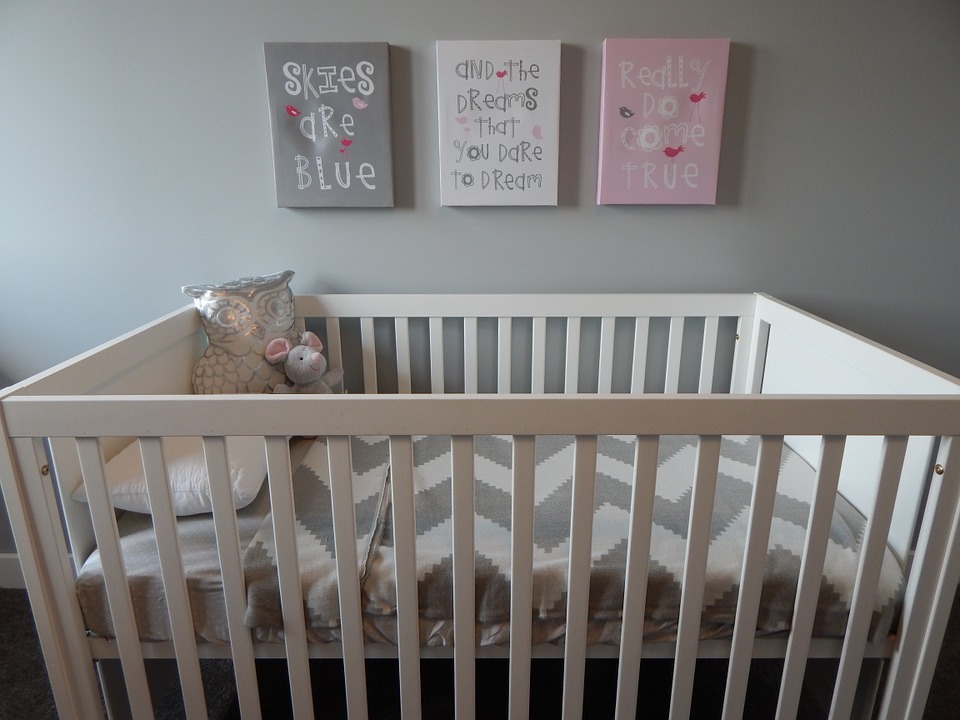 a white wooden baby crib in a nursery room with cute wall decorations