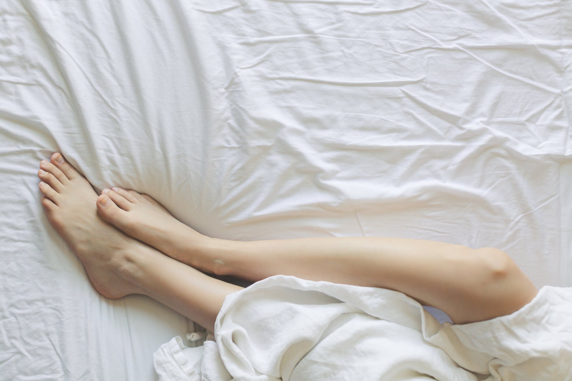 legs of a woman lying in bed and covered with a blanket