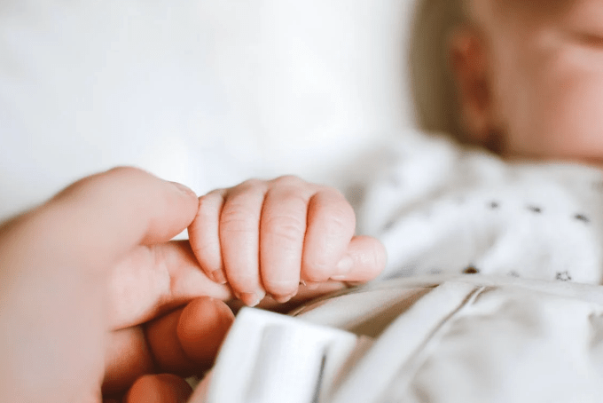 A baby holding a person’s finger