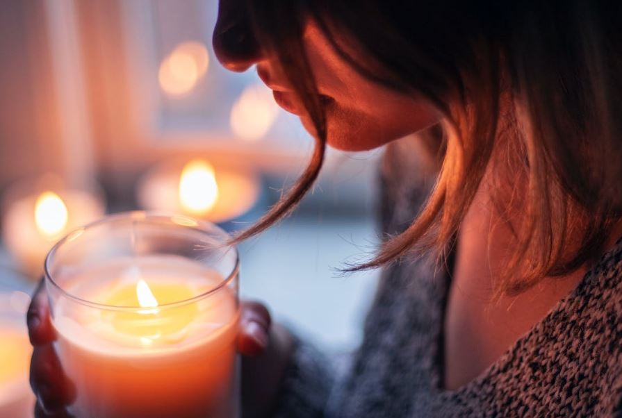 Woman holding the lighted candle in a glass container