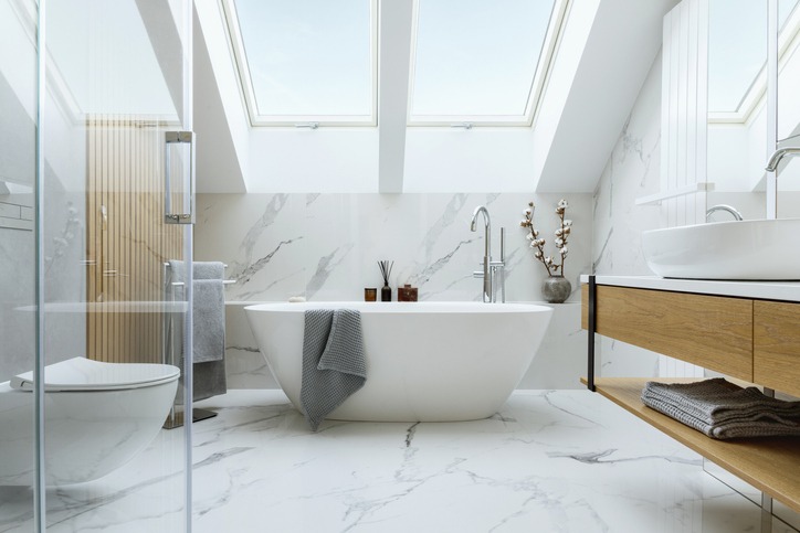 Stylish bathroom interior design with marble panels. Bathtub, towels and other personal bathroom accessories. Modern glamour interior concept. Roof window. Template."n