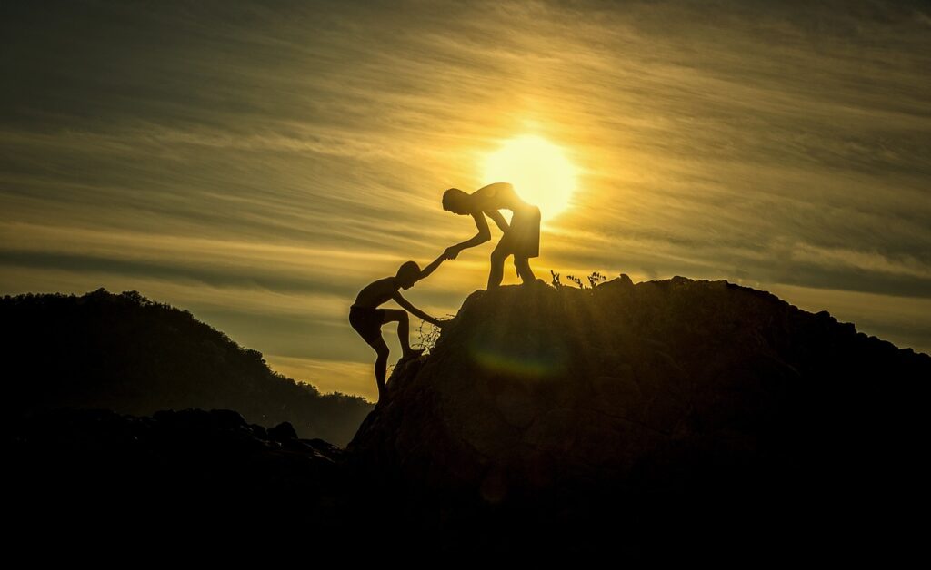 Sunset Men Silhouettes climbing on a mountain