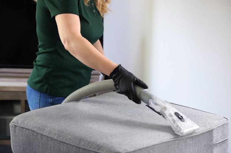 A person vacuuming a mattress with a vacuum cleaner